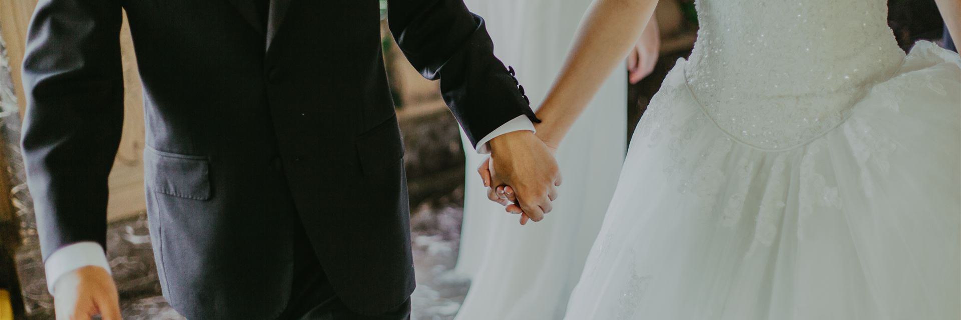 Frau, Die Weißes Brautkleid Hält, Das Hände Mit Mann Beim Gehen Hält