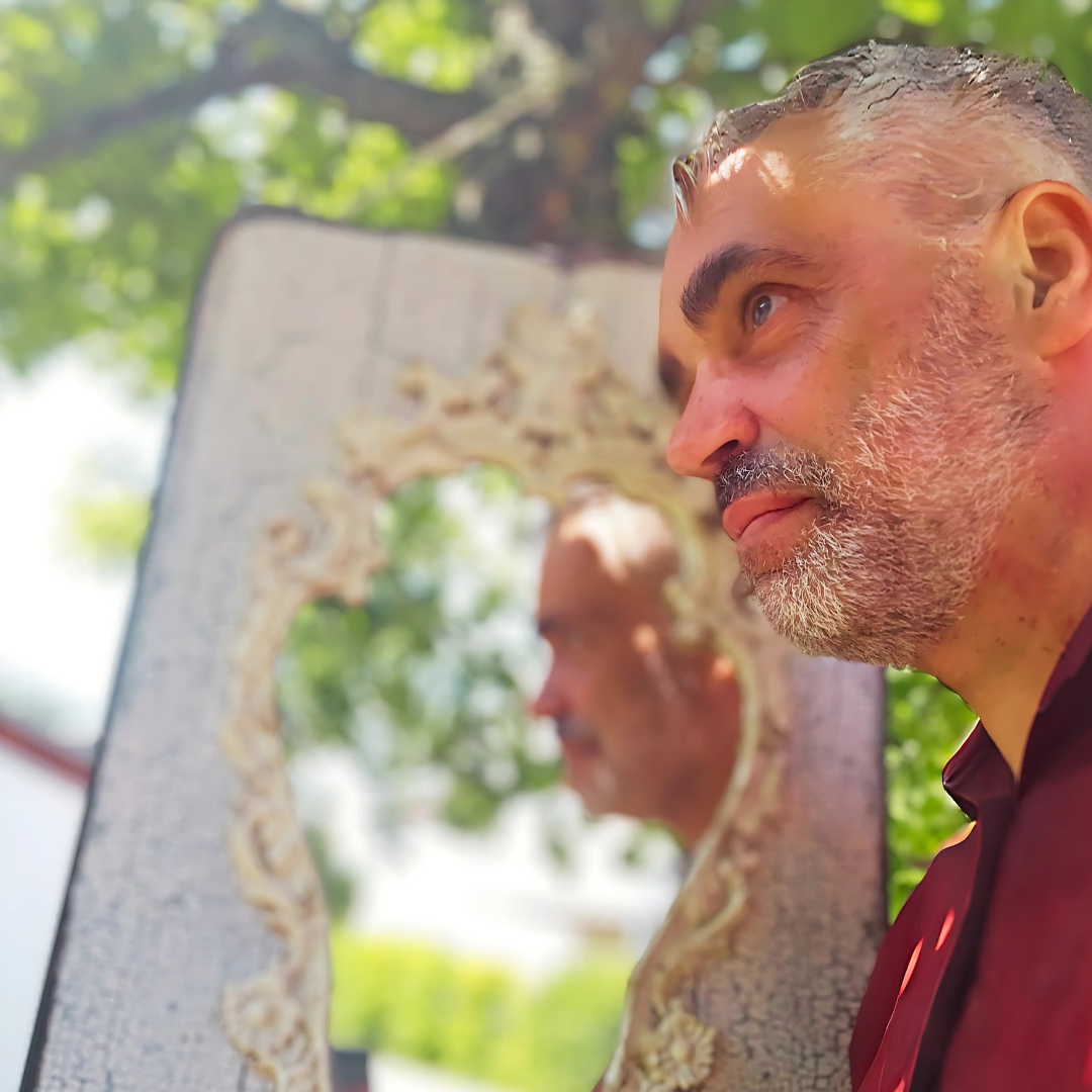 Zusehen ist DJ TOM Joe alias Thomas Joseph und in einem Spiegel, aufgehangen am Baum mit grünen Blättern, bei einer Jochzeit. Sein Spiegelbild ist zu sehen.