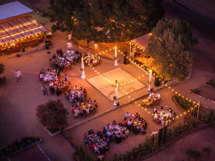 Eine Drohne fängt eine lebhafte Abendparty im Freien mit Lichterketten und dekorierten Tischen ein.