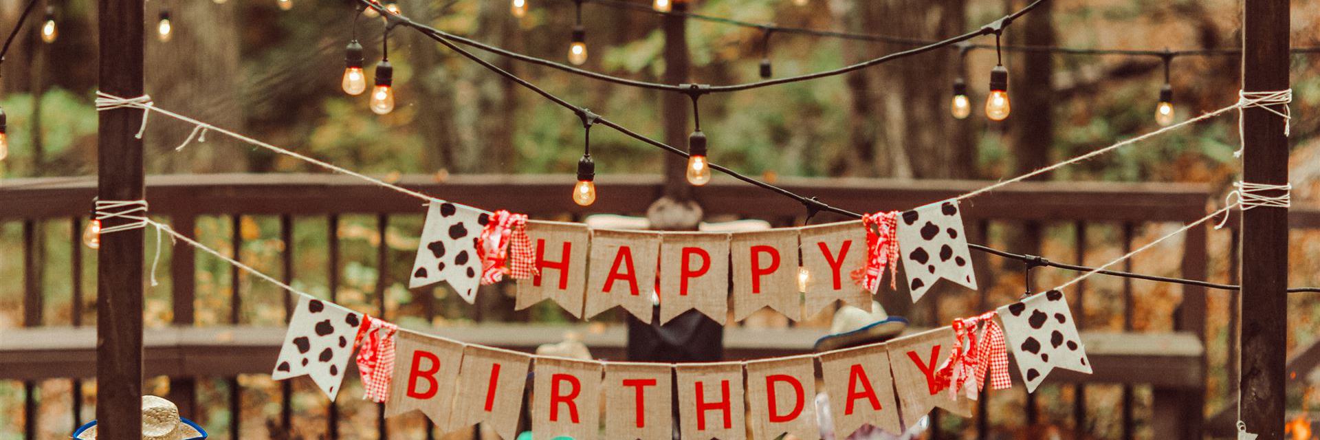 Menschen feiern einen Geburtstag und unterhalten sich - davor ein Schild mit dem Schriftzug