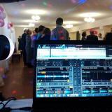 Im Vodergrund ist DJ Technik zu erkennen, im Hintergrund feiern Menschen ausgelassen.