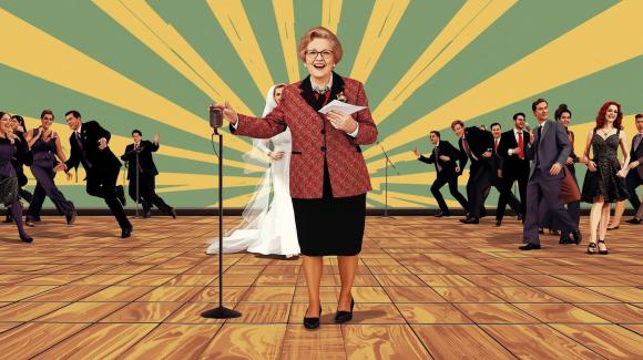 Ältere Frau mit Mikrofon hält eine Rede vor Brautpaar und Hochzeitsgästen auf der Tanzfläche – Symbol für falschen Zeitpunkt von Reden und Spielen bei Hochzeiten