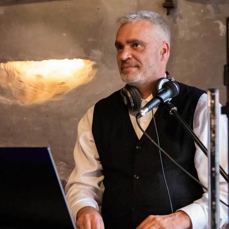 DJ Tom Joe steht bei einer Hochzeit auf Schloss Diedersdorf hinter sein DJ Pult und begleitet ein Hochzeitspiel.
